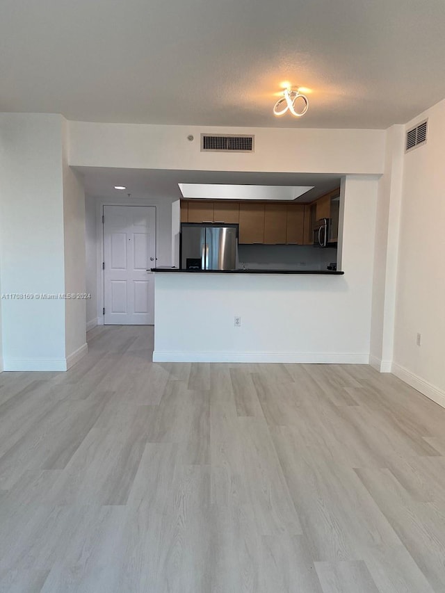 unfurnished living room featuring light hardwood / wood-style floors and a textured ceiling