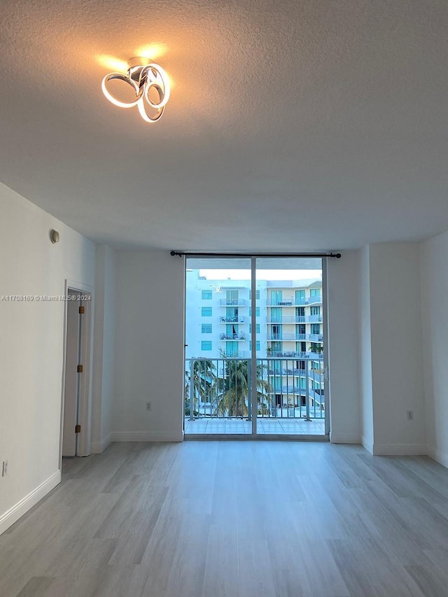 spare room with a textured ceiling, hardwood / wood-style flooring, and floor to ceiling windows