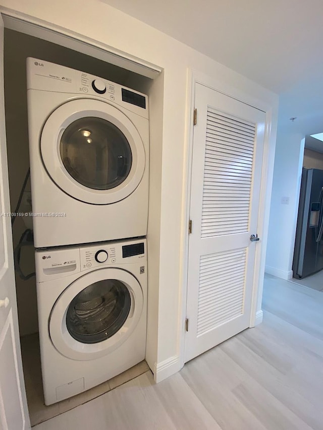 laundry area with stacked washer and dryer and light hardwood / wood-style flooring