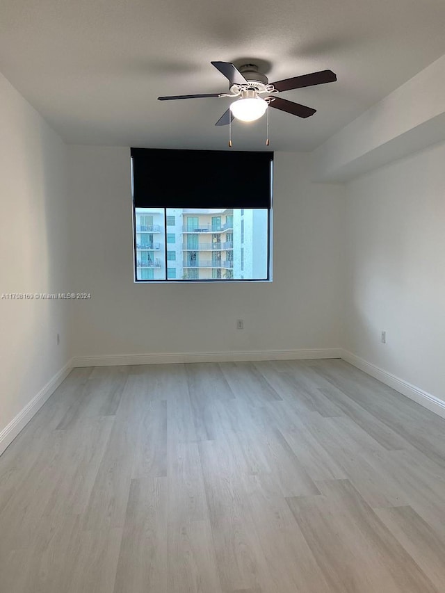 empty room with ceiling fan and light hardwood / wood-style flooring