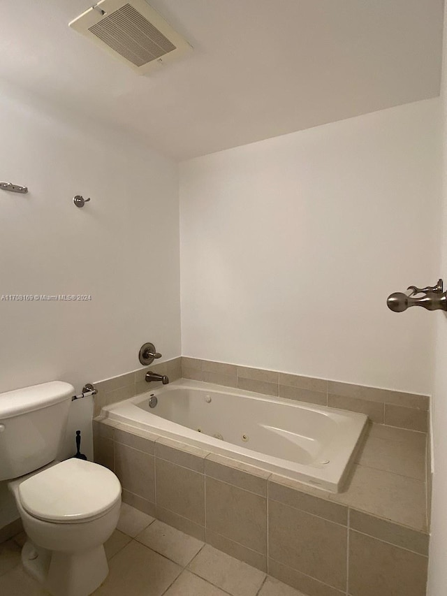 bathroom with tile patterned flooring, tiled bath, and toilet