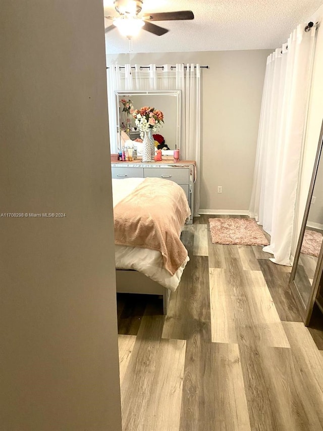 bedroom featuring ceiling fan, hardwood / wood-style floors, and a textured ceiling