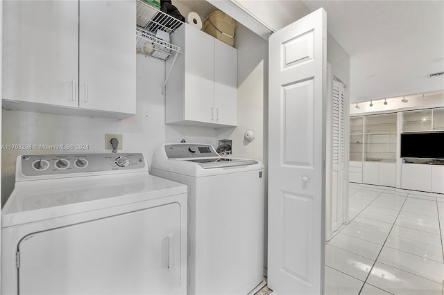 laundry area featuring cabinets, light tile patterned floors, and washer and dryer