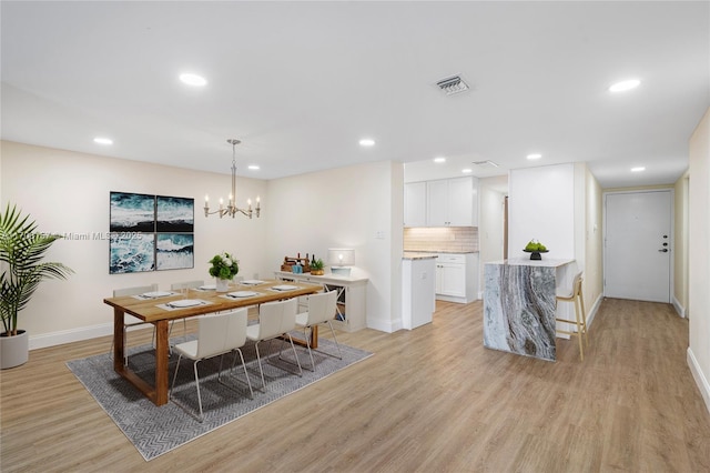 dining room featuring light wood-style floors, baseboards, a chandelier, and visible vents