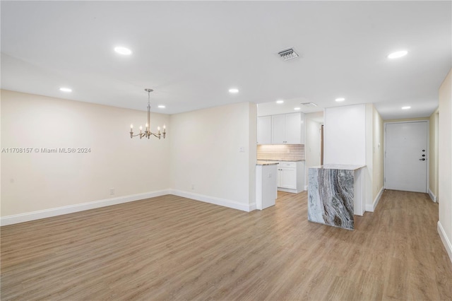 unfurnished living room with a chandelier and light hardwood / wood-style flooring