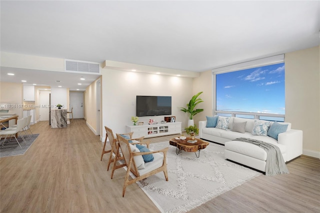 living area featuring baseboards, light wood finished floors, and visible vents