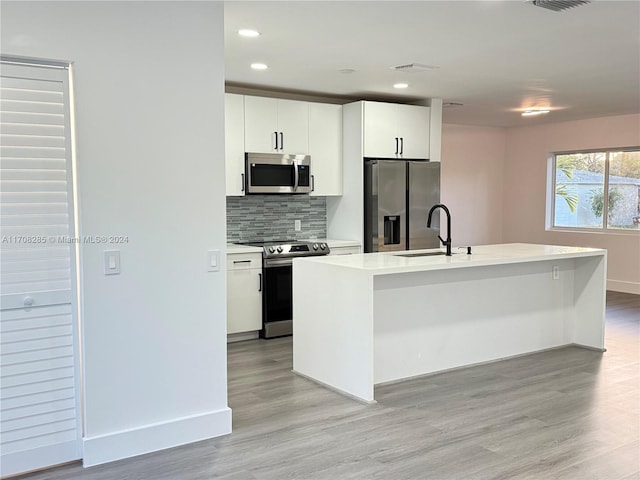 kitchen featuring a center island with sink, light hardwood / wood-style floors, white cabinets, and stainless steel appliances