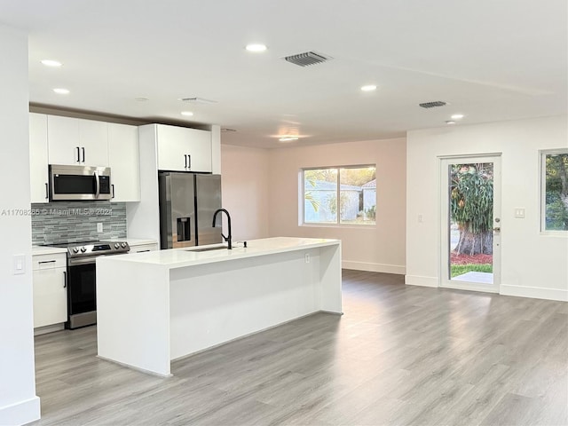 kitchen with a healthy amount of sunlight, sink, stainless steel appliances, and a kitchen island with sink