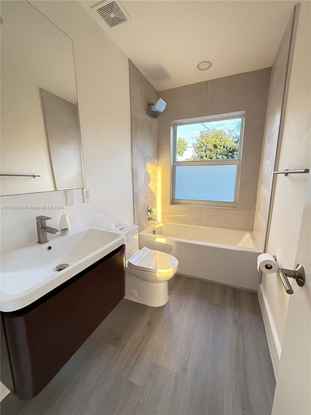 full bathroom with vanity, toilet, tiled shower / bath, and hardwood / wood-style flooring