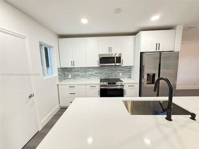 kitchen featuring sink, dark hardwood / wood-style floors, tasteful backsplash, white cabinetry, and stainless steel appliances