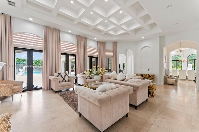 living room featuring french doors, coffered ceiling, beamed ceiling, a towering ceiling, and a chandelier