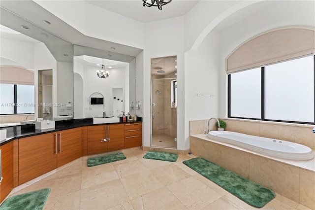 bathroom featuring separate shower and tub, a towering ceiling, vanity, and a notable chandelier