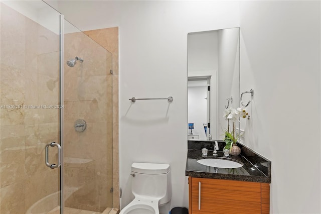 bathroom featuring toilet, an enclosed shower, and vanity