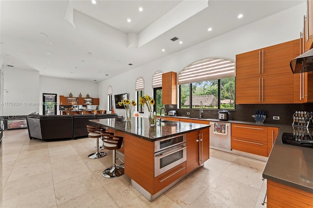 kitchen featuring a center island, a kitchen breakfast bar, sink, dark stone countertops, and stainless steel appliances