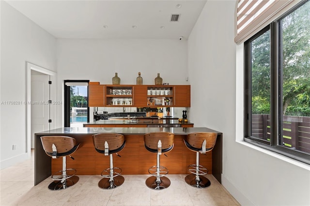 kitchen with kitchen peninsula, a breakfast bar, and light tile patterned flooring