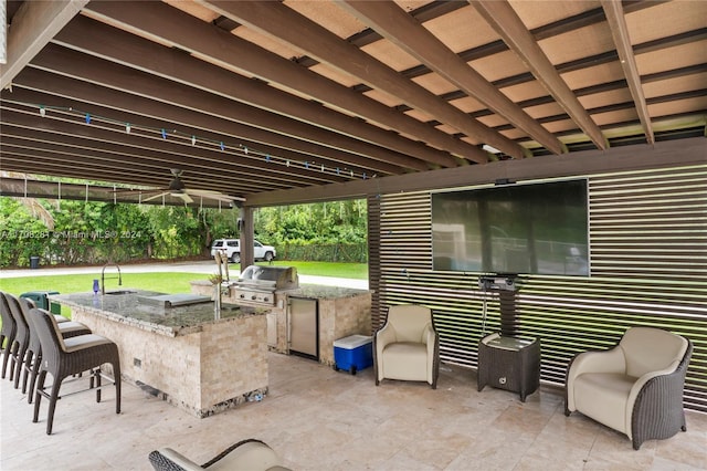 view of patio with a bar, an outdoor kitchen, grilling area, and ceiling fan