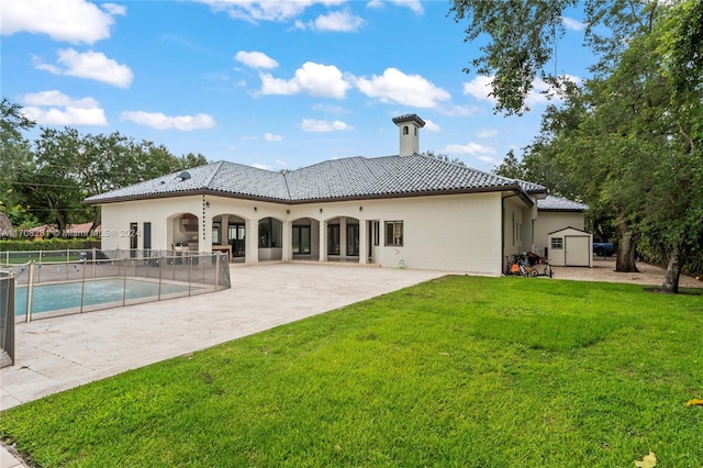 back of property featuring a fenced in pool, a patio area, a yard, and a storage unit