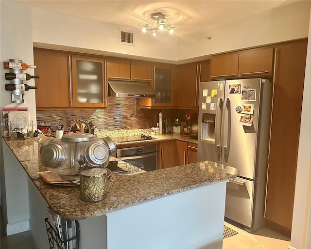 kitchen with stone counters, tasteful backsplash, kitchen peninsula, light tile patterned flooring, and appliances with stainless steel finishes