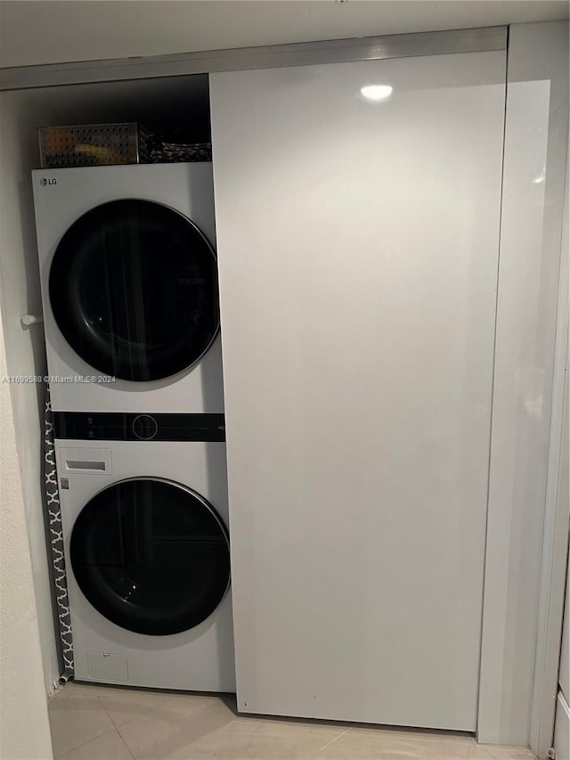 laundry area featuring light tile patterned floors and stacked washer and dryer