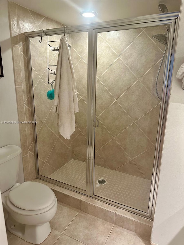 bathroom with toilet, tile patterned floors, and a shower with shower door