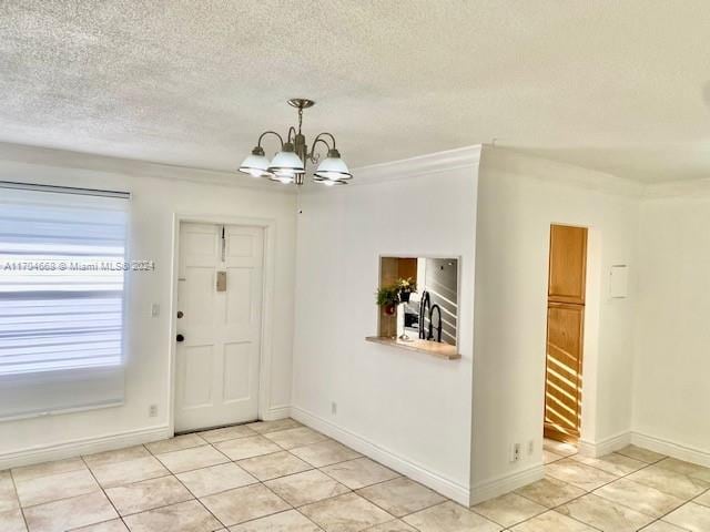 tiled foyer with ornamental molding, a textured ceiling, and a chandelier