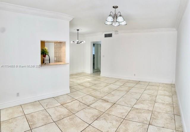 unfurnished room featuring light tile patterned floors, ornamental molding, and a notable chandelier