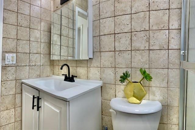 bathroom with vanity, toilet, and tile walls