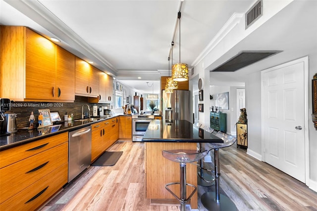 kitchen featuring sink, backsplash, a breakfast bar, appliances with stainless steel finishes, and light wood-type flooring