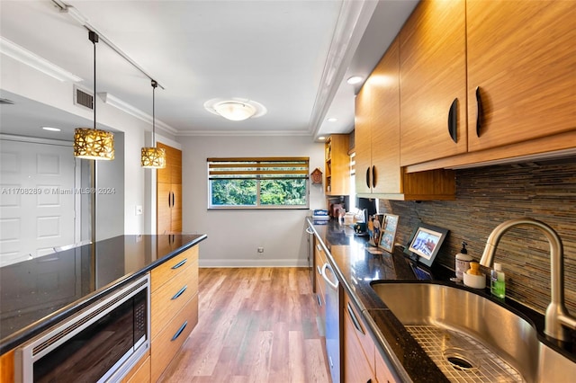 kitchen featuring pendant lighting, crown molding, sink, light wood-type flooring, and appliances with stainless steel finishes