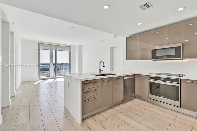 kitchen with kitchen peninsula, black electric stovetop, expansive windows, stainless steel oven, and sink