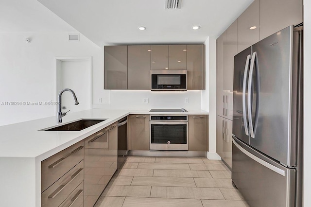 kitchen featuring kitchen peninsula, appliances with stainless steel finishes, gray cabinetry, and sink