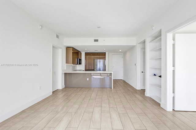 kitchen with a kitchen bar, kitchen peninsula, stainless steel fridge, and built in features