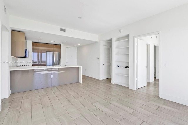 kitchen with a kitchen breakfast bar, stainless steel refrigerator, kitchen peninsula, and light hardwood / wood-style floors