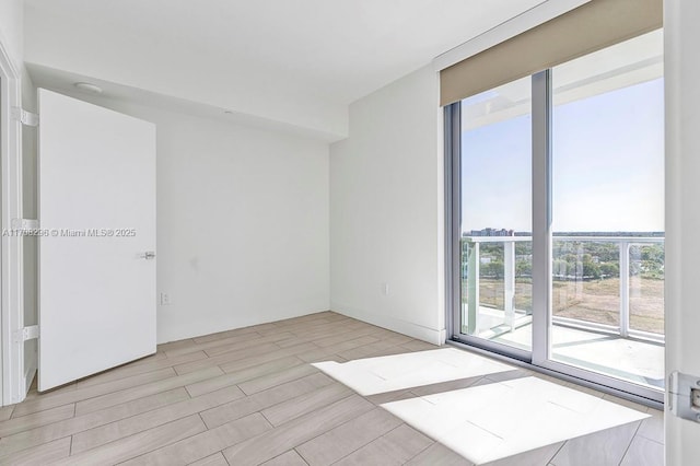 unfurnished room with plenty of natural light, light hardwood / wood-style floors, and expansive windows