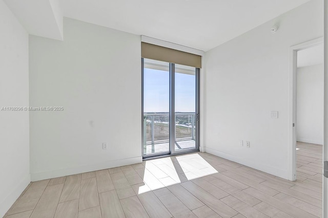 empty room with floor to ceiling windows and light wood-type flooring