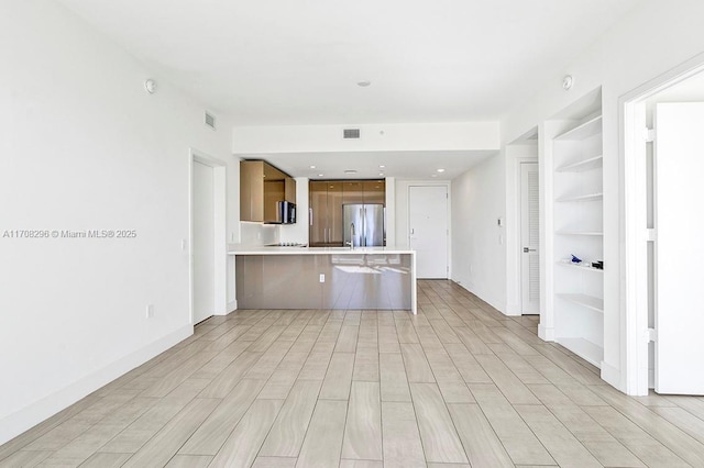 kitchen featuring kitchen peninsula, stainless steel fridge, built in features, and a kitchen breakfast bar