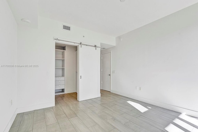 unfurnished bedroom with a barn door, a spacious closet, and a closet