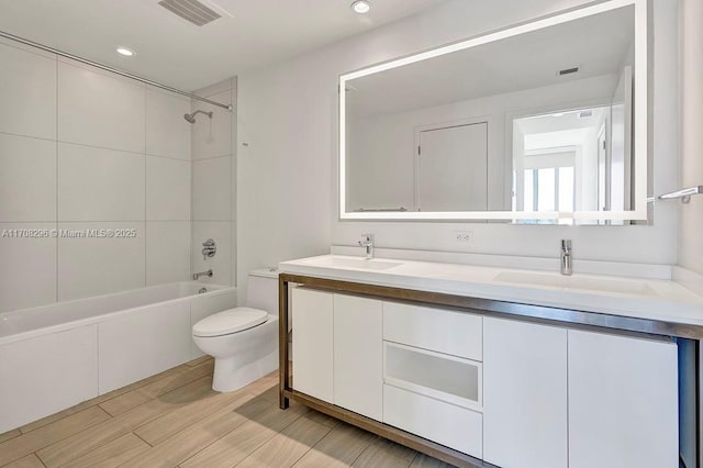 full bathroom featuring vanity, tiled shower / bath combo, and toilet