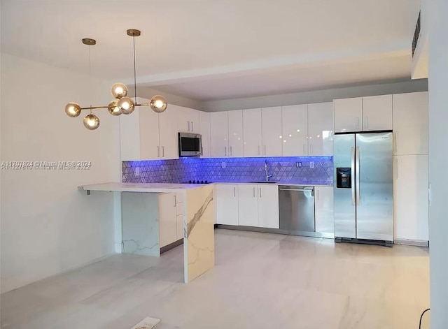 kitchen featuring decorative backsplash, stainless steel appliances, sink, pendant lighting, and white cabinetry