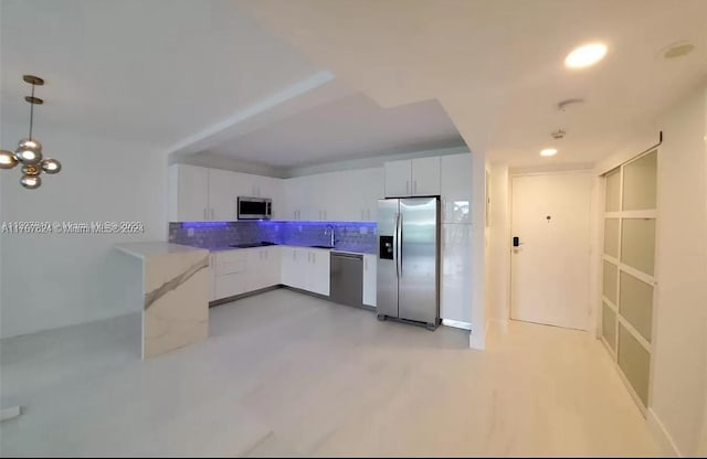 kitchen featuring tasteful backsplash, white cabinets, hanging light fixtures, and appliances with stainless steel finishes