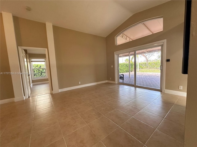 unfurnished room with a wealth of natural light, light tile patterned floors, and lofted ceiling