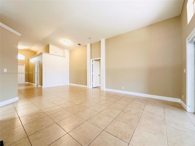 tiled empty room featuring vaulted ceiling