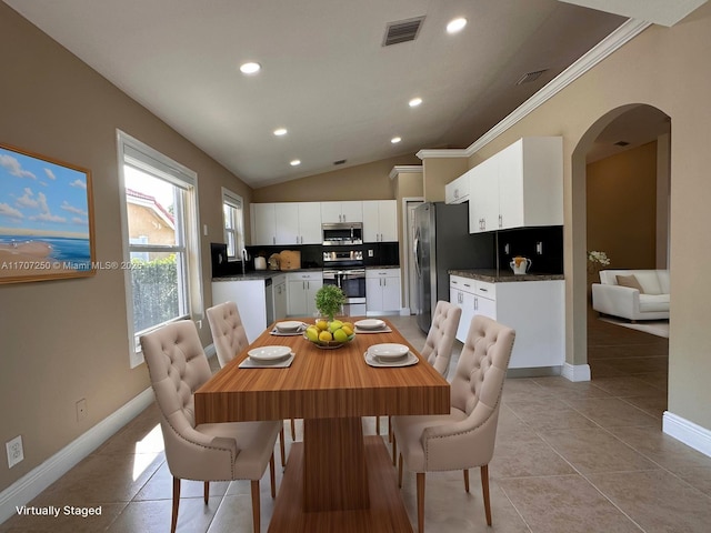 dining area featuring sink, crown molding, lofted ceiling, and light tile patterned flooring