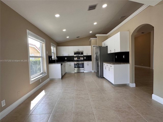 kitchen featuring white cabinets, appliances with stainless steel finishes, lofted ceiling, sink, and light tile patterned floors