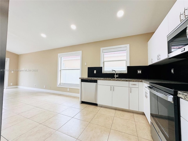 kitchen with white cabinetry, stainless steel appliances, and dark stone countertops