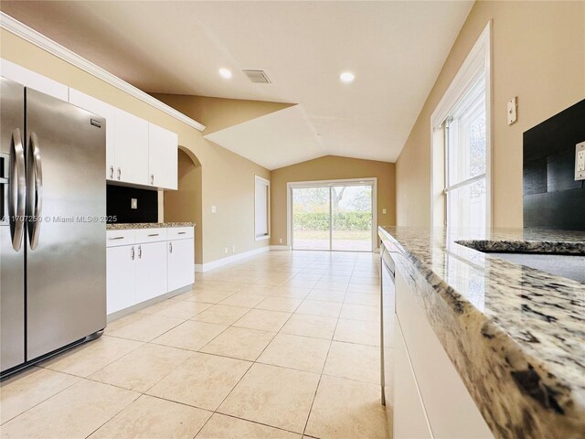 kitchen with stainless steel fridge with ice dispenser, lofted ceiling, white cabinets, and light stone countertops