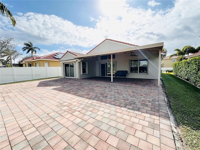 rear view of property featuring ceiling fan and a patio area