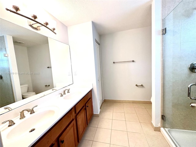 bathroom with vanity, toilet, a shower with door, tile patterned floors, and a textured ceiling