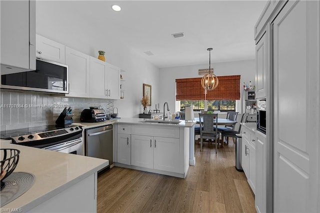 kitchen featuring white cabinets, kitchen peninsula, sink, and appliances with stainless steel finishes