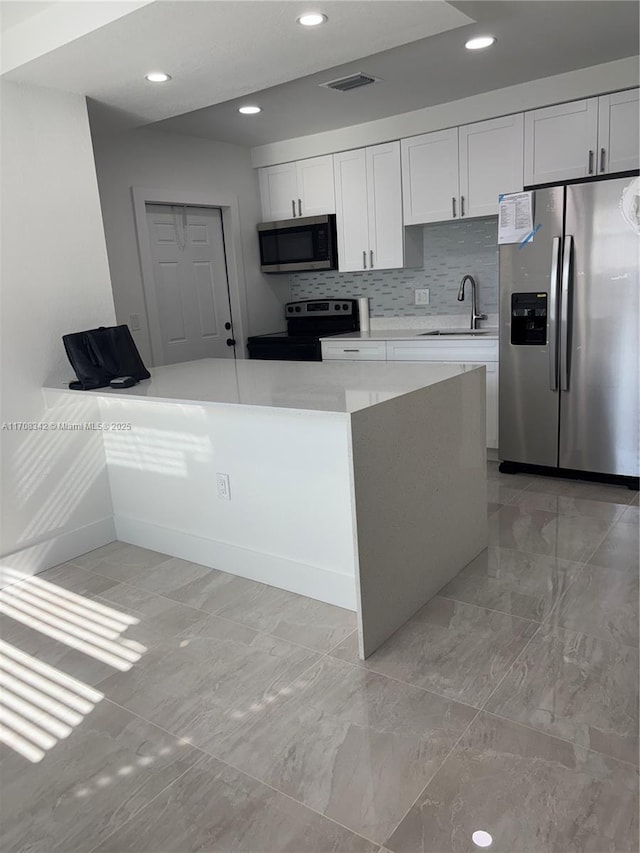 kitchen with tasteful backsplash, white cabinetry, sink, and stainless steel appliances